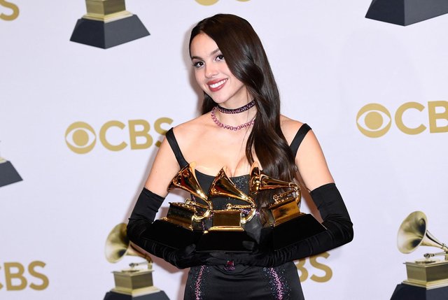 Courtesy of Patrick T. Fallon/Getty Images. Singer Olivia Rodrigo poses with awards.