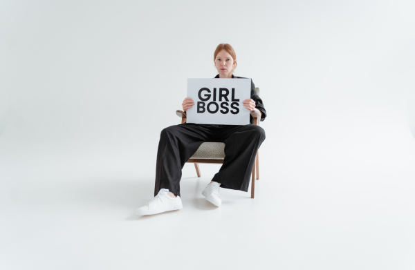 Woman Sitting While Holding a Girl Boss Postcard, courtesy of Tima Miroshnichenko.