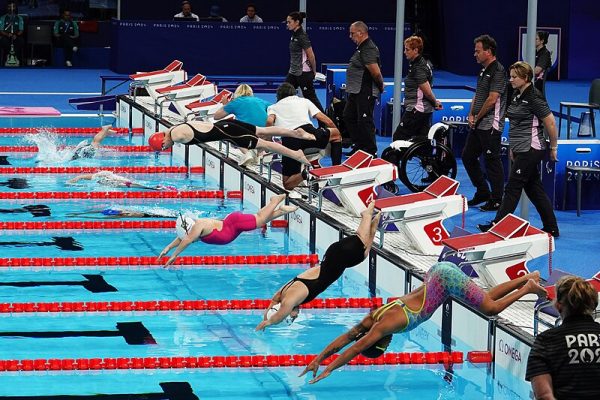 Para swimmers dive into the water.