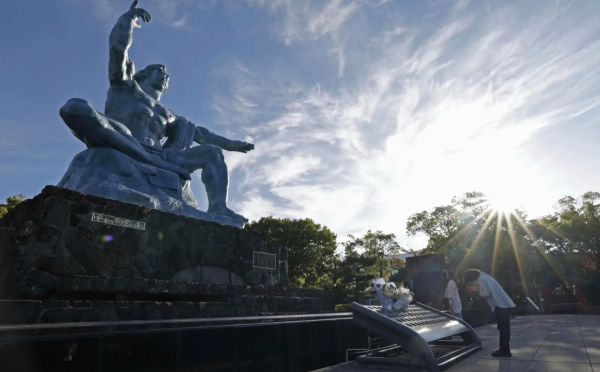 Japanese woman prays in front of the Peace Park statue in Nagasaki.