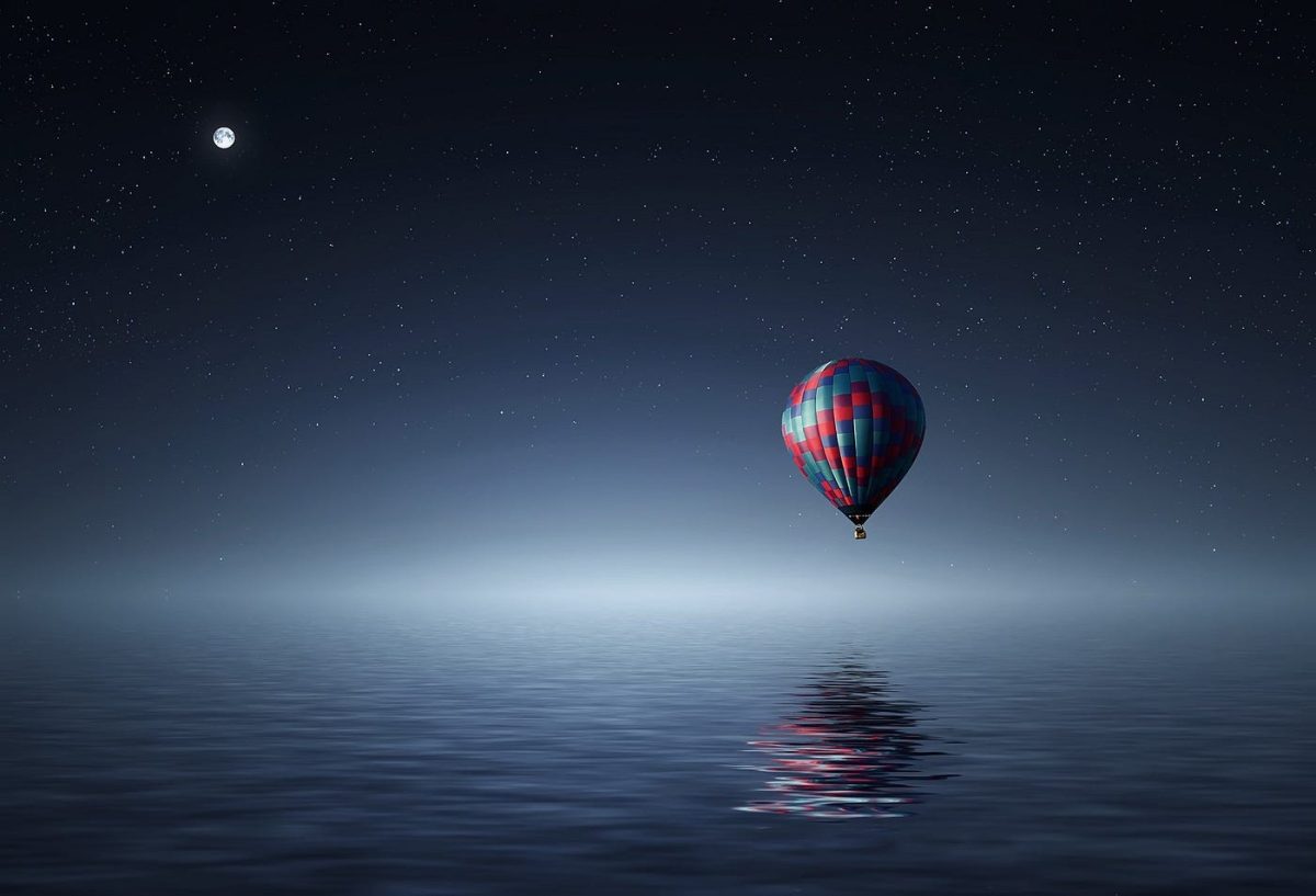 A dreamlike balloon over the open ocean at night.