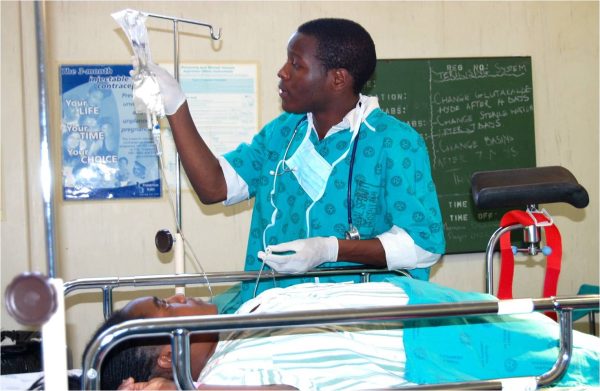 An ill woman looks at her doctor as he checks on her Intravenous medication.